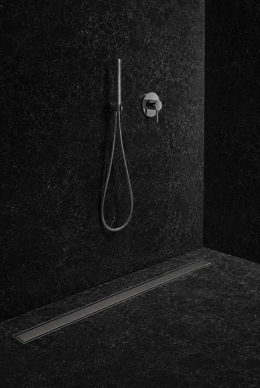 X4 Design and Build black marble shower area with linear floor drain, chrome hand shower, dark stone walls, and modern bathroom drainage detail